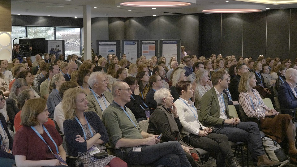 publiek symposium 30 jaar PGT met op de achtergrond posterborden